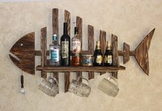 a wooden fish shaped shelf with wine glasses and liquor bottles on it, hanging from the wall