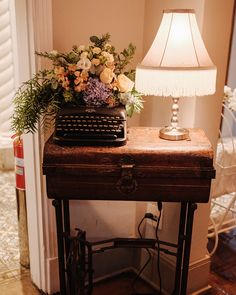 an old fashioned typewriter sitting on top of a wooden table next to a lamp