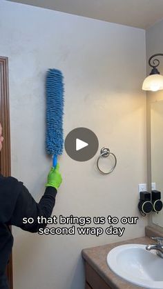 a woman is cleaning the bathroom with a blue scrubber and green gloves on her head