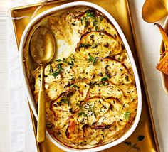 a casserole dish with cheese and vegetables in it on a gold serving tray