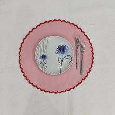 a pink and white plate with blue flowers on it next to a fork and knife