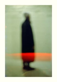 a blurry image of a person standing in front of a red object on the ground