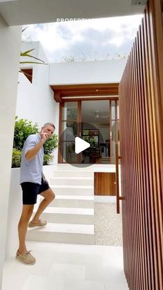 a man standing in front of a house talking on a cell phone