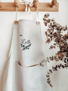 an apron hanging on a wooden rack next to a potted plant