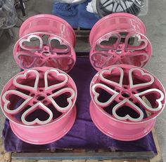 four pink wheels with hearts on them sitting on a purple cloth