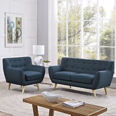 a living room with two blue couches and a coffee table in front of a large window