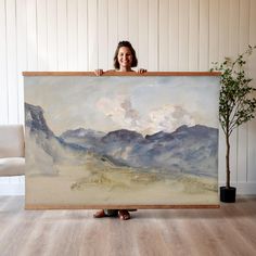 a woman holding up a large painting in front of her face