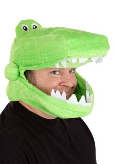 a man wearing a green alligator hat with teeth on it's head and mouth wide open