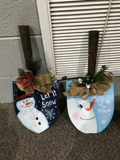 two snowman stocking hanging from the side of a building next to a window