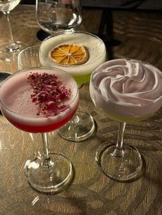 three glasses filled with different types of drinks on top of a wooden table next to each other