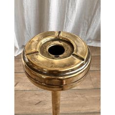 a gold colored stool with a black hole in the middle and wood flooring around it