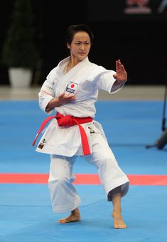 a woman standing on top of a blue floor holding a red belt in her hand