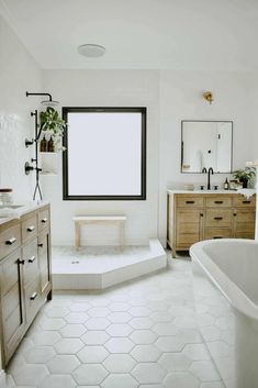 a large bathroom with white tile floors and wooden cabinetry on the wall, along with a tub