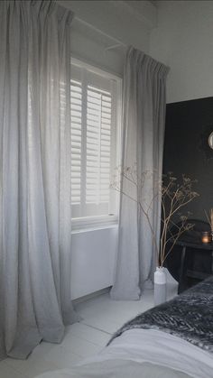 a bedroom with white curtains and a bed in front of a window filled with candles