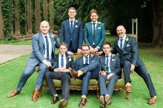 a group of men sitting on top of a green couch in front of trees and grass