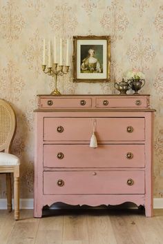 a pink dresser sitting next to a white chair