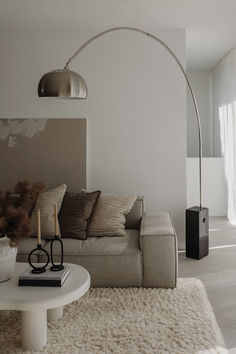 a living room with a couch, table and lamp on the wall next to it