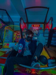 a man sitting on top of a skateboard in a room filled with arcade machines