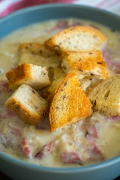 a blue bowl filled with soup and croutons sitting on top of a table