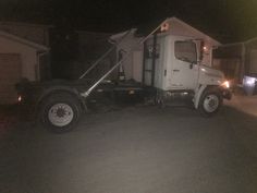 a white truck parked in front of a house at night with the door open and lights on