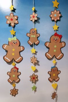 three hanging gingerbreads with stars and hearts attached to strings on a blue background