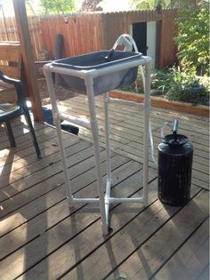 a black trash can sitting on top of a wooden deck next to a water tank