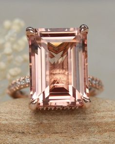 a pink diamond ring sitting on top of a rock