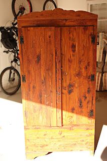 an old wooden armoire sitting in the middle of a room with bikes on the wall