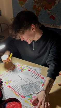 a person sitting at a table with a drawing on it and a lit candle in front of them