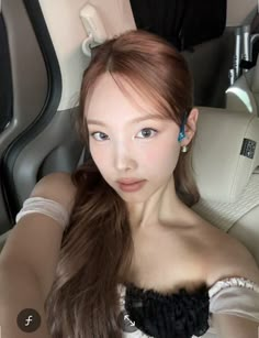 a woman with long hair sitting in the back seat of a car looking at the camera