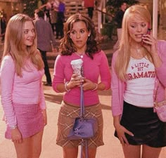 the mean girls are talking on their cell phones and one is holding a drink in her hand