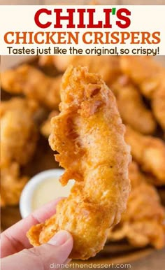 a person holding up a fried chicken nugget in front of some dipping sauce