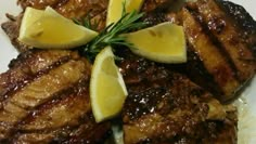 grilled meat with lemon wedges and rosemary garnish