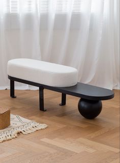 a white bench sitting on top of a hard wood floor next to a basket and window