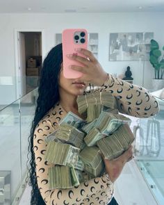 a woman taking a selfie with her phone and stacks of money in front of her