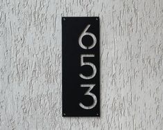 a black and white house number sign mounted to the side of a building