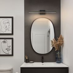 a bathroom with a sink, mirror and toilet in it's corner area next to pictures on the wall