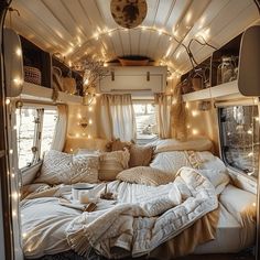 the interior of a camper with lights strung from the ceiling and pillows on the bed