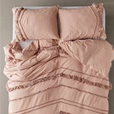 a bed with pink sheets and pillows on it