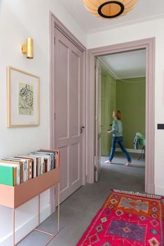 a woman walking into a room with pink doors and an area rug on the floor