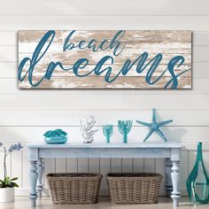 a wooden sign with the words beach dreams on it next to baskets and vases