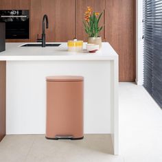 a kitchen with a sink, stove and trash can on the counter next to it