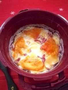 a pot filled with food sitting on top of a red tablecloth covered table next to utensils