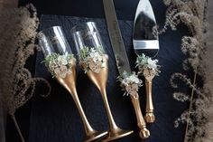 three gold vases with flowers on them next to a knife and some other items