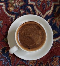 there is a cup of coffee on the saucer and carpeted tablecloths