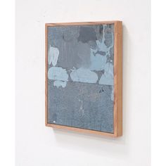 a painting hanging on the wall in front of a white wall with a wooden frame