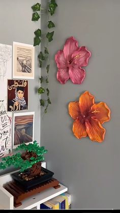 there are two flowers on the wall next to each other and one flower is pink