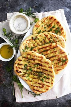 grilled flatbreads with herbs and seasoning on a plate next to dipping sauce