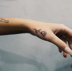 a woman's left hand with a small tattoo on the middle finger and wrist