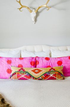 a bed with pink pillows and a deer head on the wall